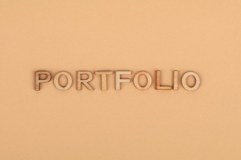 Close-up of wooden letters spelling 'PORTFOLIO' on a yellow background, offering creative copyspace.