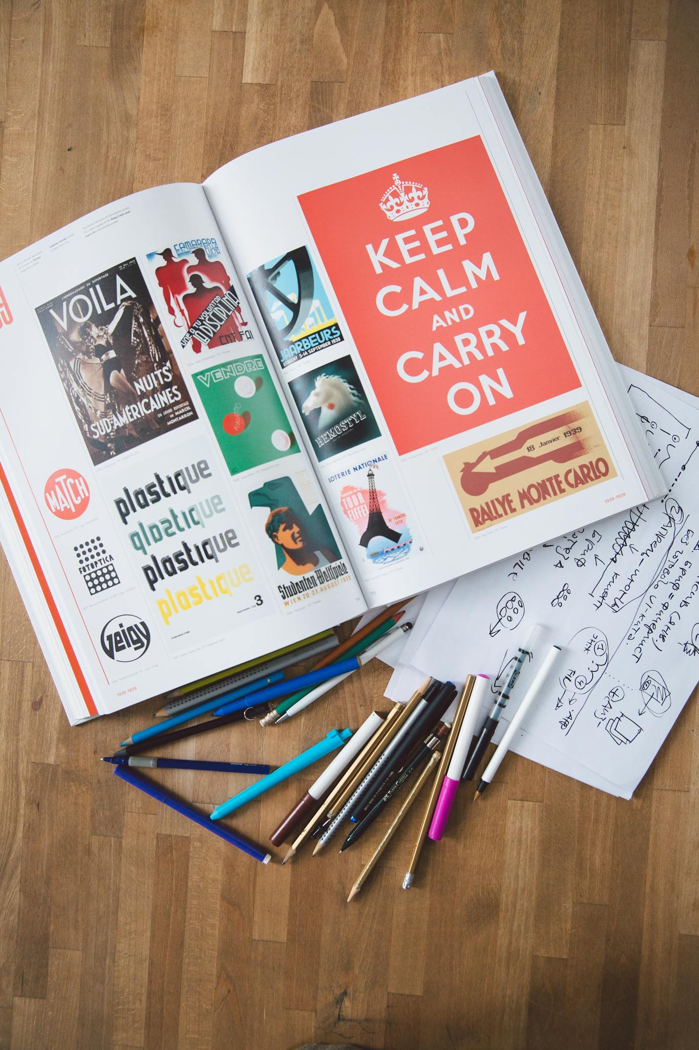 Open book with design elements and pencils on a wooden desk, perfect for creative projects.